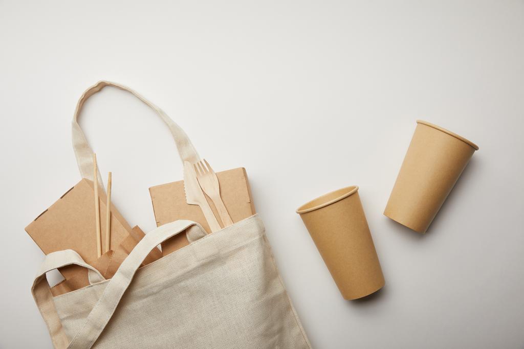 επίπεδη lay με βαμβακερή τσάντα με κιβώτια τροφίμων και δύο φλιτζάνια καφέ μίας χρήσης σε λευκή επιφάνεια - Φωτογραφία, εικόνα