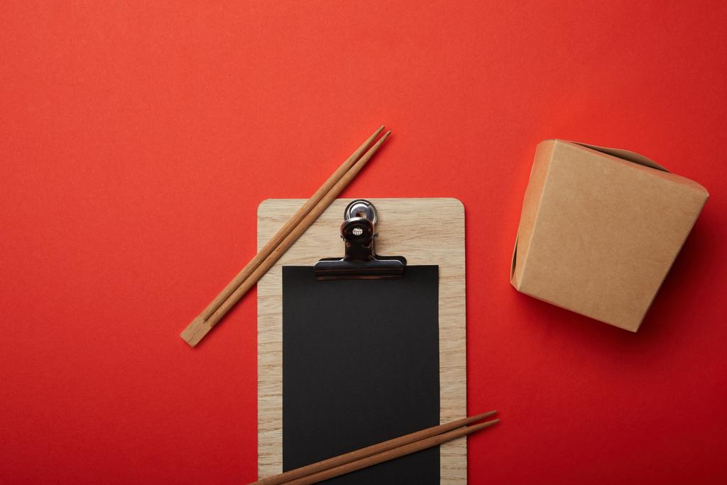 görücü usulü makarna kutusu, yemek çubukları ve kırmızı yüzeyinde boş siyah menü yukarıdan görüntülemek - Fotoğraf, Görsel