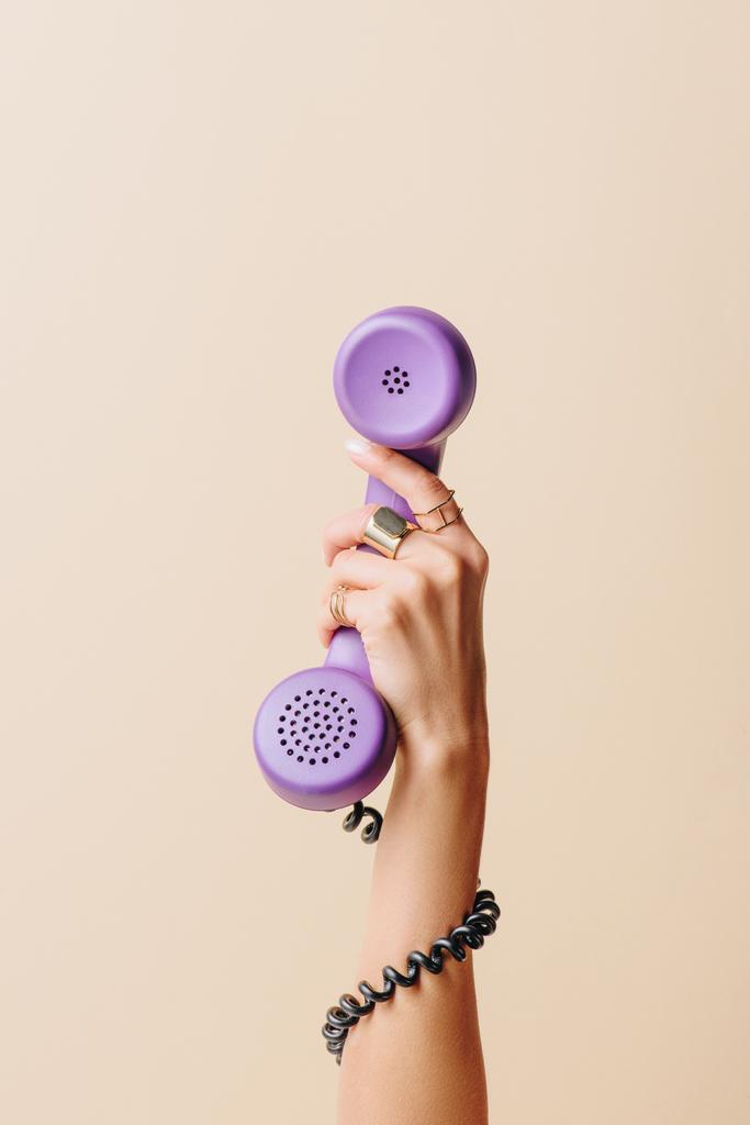 gedeeltelijke weergave van vrouw met paarse telefoon buis op beige - Foto, afbeelding