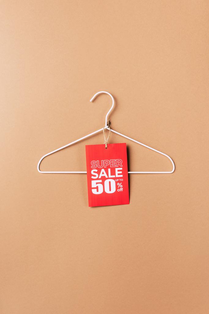Kleiderbügel mit rotem Super Sale Tag mit fünfzig Prozent Rabatt auf beige - Foto, Bild
