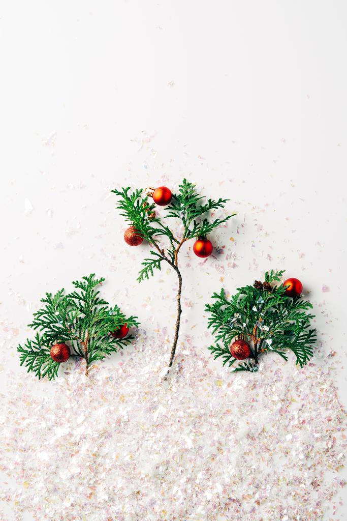 pose plate avec des branches de pin décorées avec des boules de Noël avec des paillettes sur la surface blanche
 - Photo, image