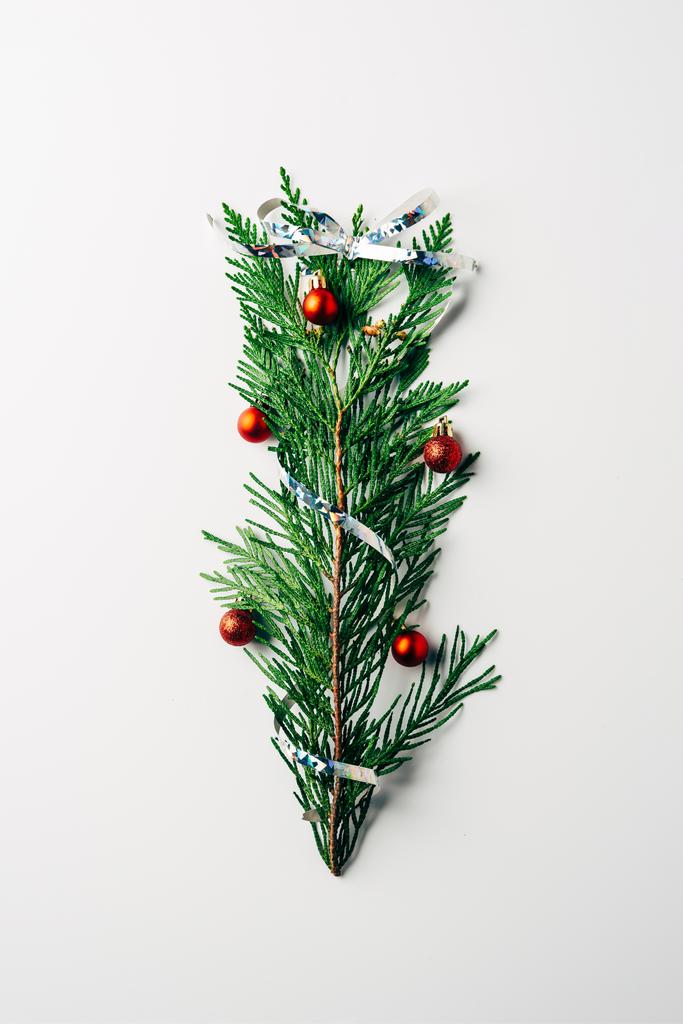 白い背景上にクリスマス ツリーとしてクリスマスのおもちゃやリボンで飾られた緑の松の枝の上から見る - 写真・画像