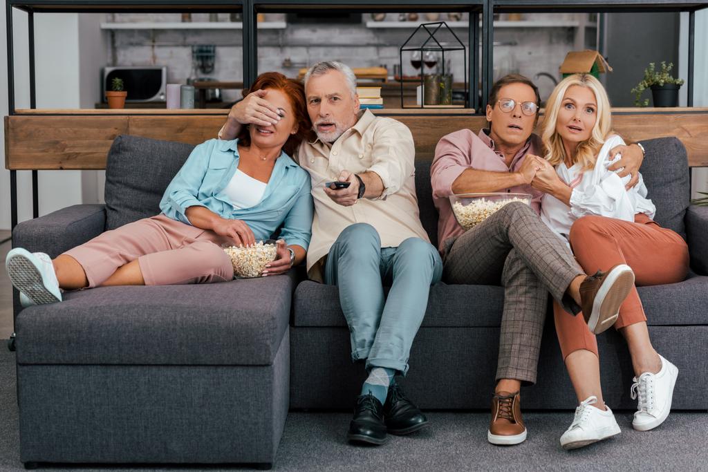 scared mature couples sitting on couch and watching tv together - Photo, Image