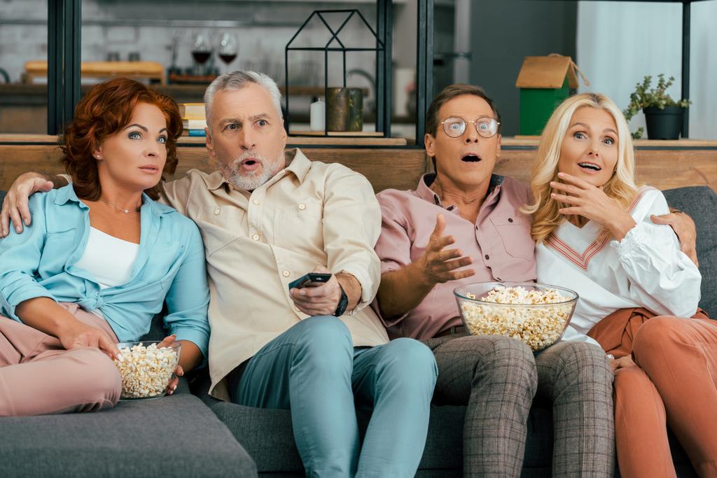 järkyttynyt kypsä ystäviä istuu sohvalla ja katsella televisiota yhdessä
 - Valokuva, kuva