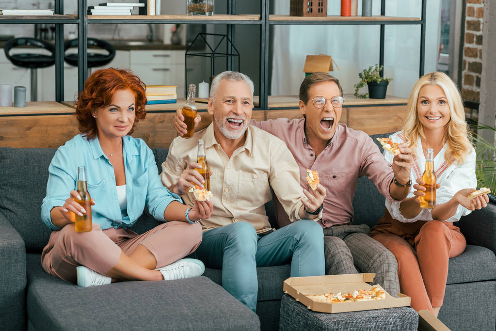 onnelliset vanhat ystävät juovat olutta ja syövät pizzaa kotona
 - Valokuva, kuva