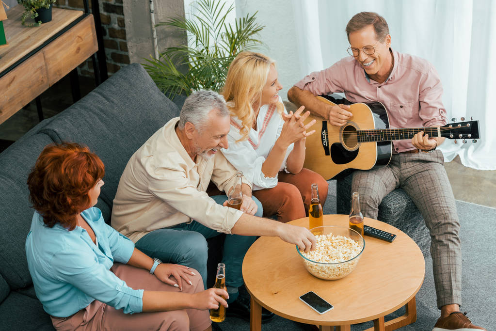 high angle view of happy old friends spending time with guitar and beer at home  - Photo, Image