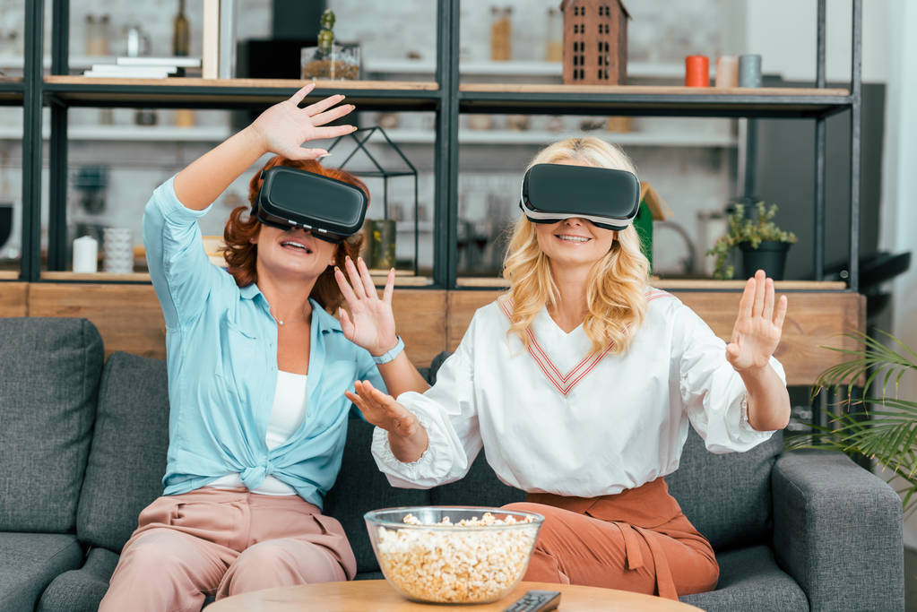 mosolygó érett női barátok segítségével virtuális valóság fejhallgatók otthon - Fotó, kép