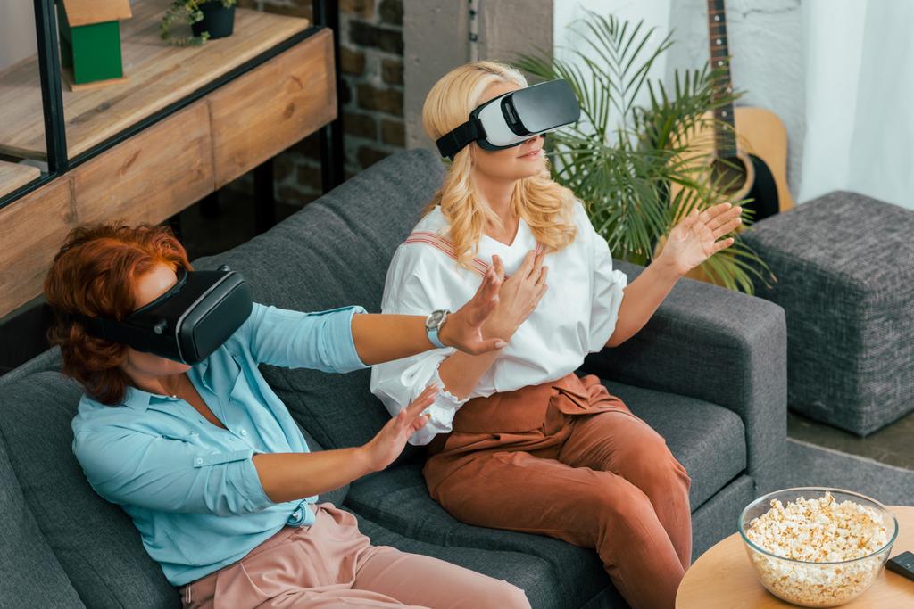 成熟した女性はソファに座っていると仮想現実のヘッドセットを使用しての高角度のビュー  - 写真・画像