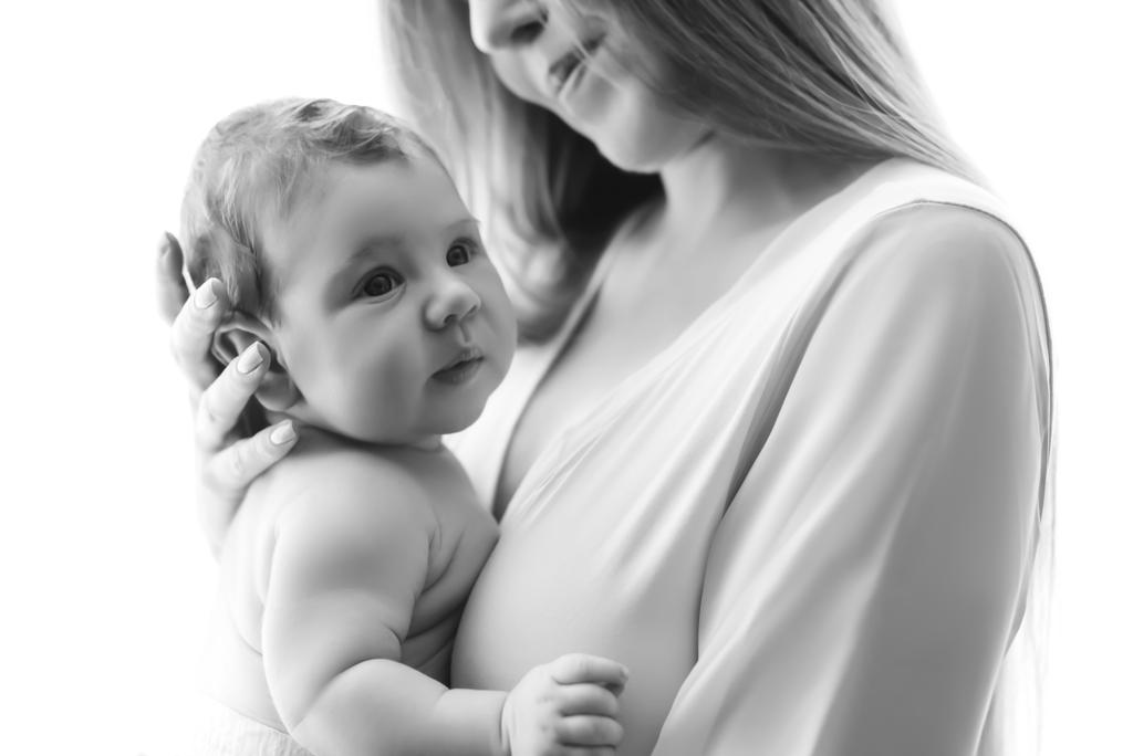 częściowy widok matka niosąca małego chłopca przed zasłony, w domu, czarno-białe - Zdjęcie, obraz
