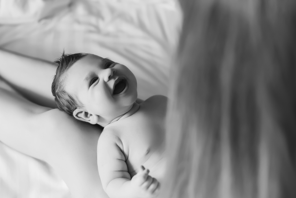 частковий вид жінки, що грає зі усміхненим маленьким хлопчиком в ліжку вдома, чорно-білим
 - Фото, зображення