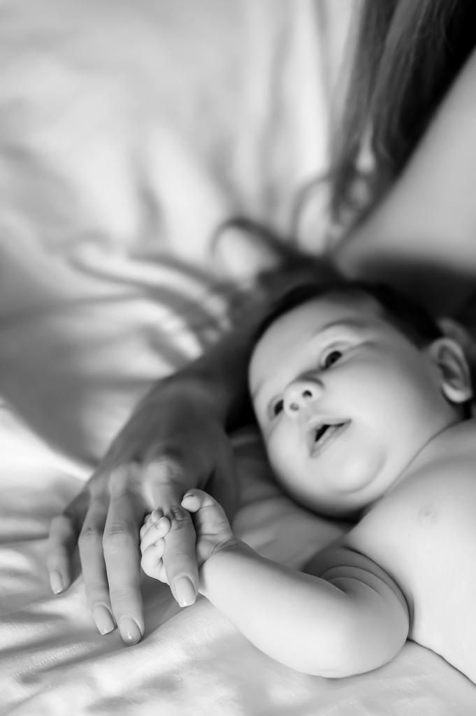 Schwarz-Weiß-Bild der Mutter, die zu Hause im Bett die Hand eines kleinen Jungen hält - Foto, Bild
