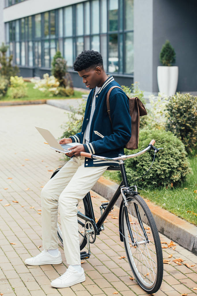 stílusos afrikai amerikai férfi, miközben ferde bicikli-városban laptop távoli munkát végző - Fotó, kép