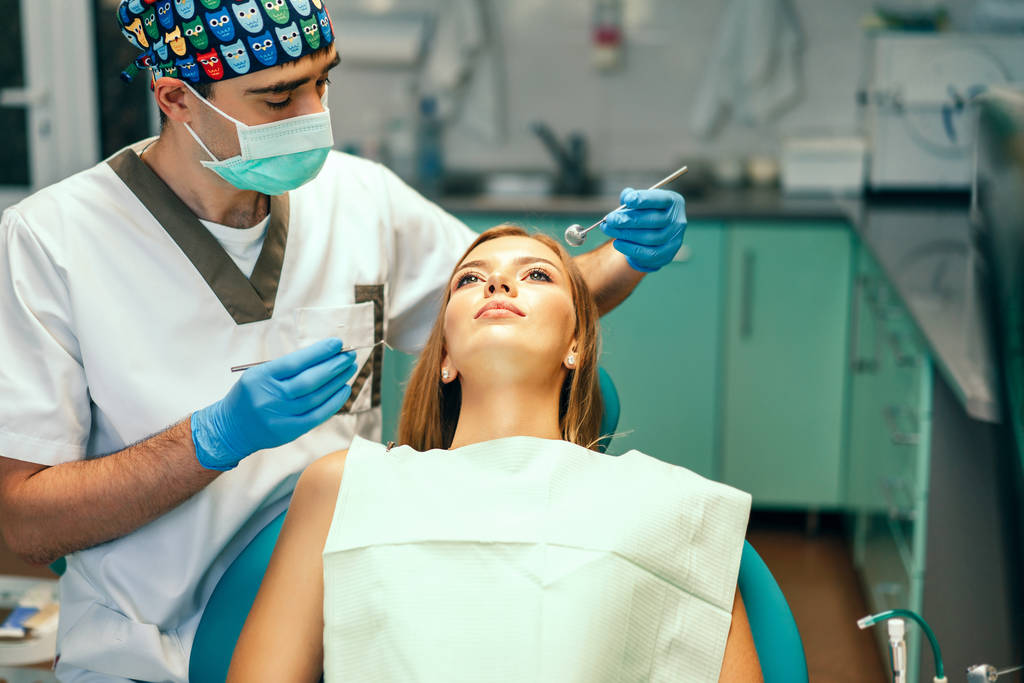 Dentista examina paciente femenina con aparatos ortopédicos en consultorio
 - Foto, Imagen