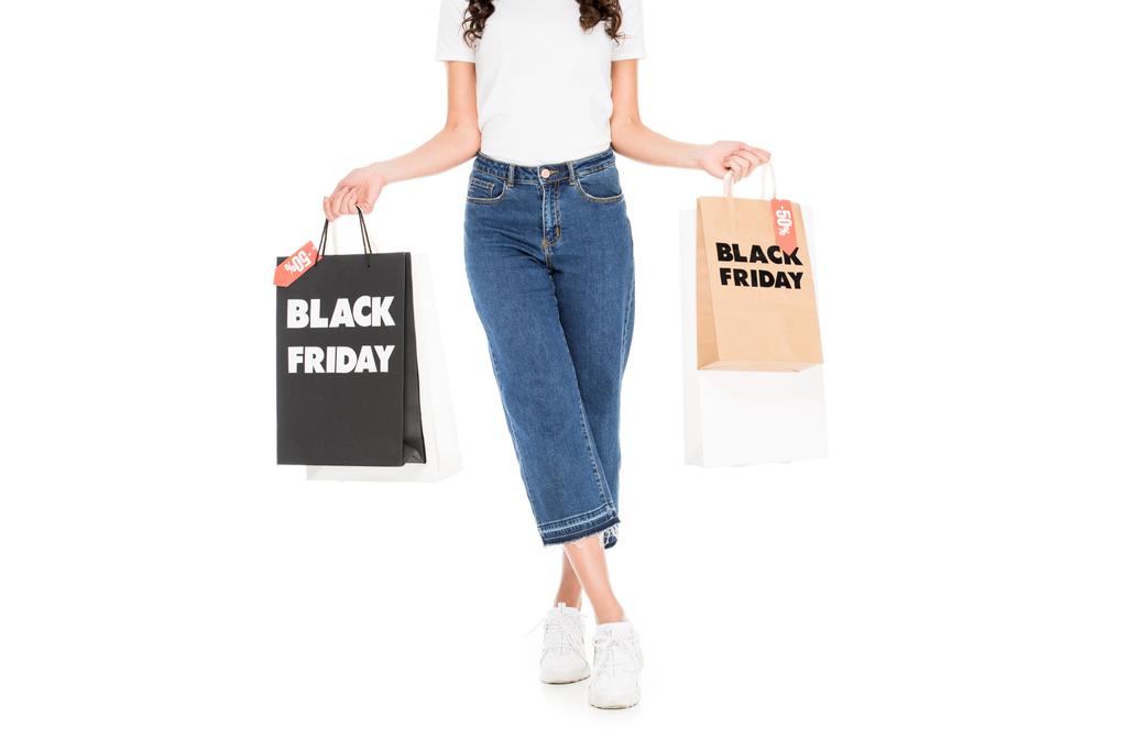 cropped view of stylish shopper holding shopping bags with black friday sale signs isolated on white - Photo, Image