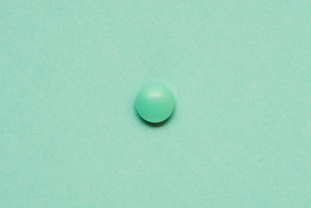 vista superior do comprimido verde redondo no fundo verde
  - Foto, Imagem