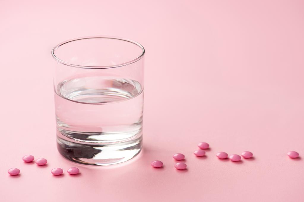 vista de primer plano del vaso de agua y tabletas médicas en rosa
   - Foto, imagen