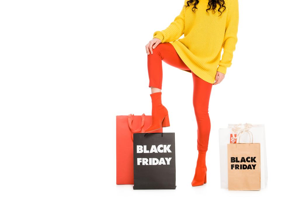 abgeschnittene Ansicht von modischen Shopaholic posiert in der Nähe von Einkaufstüten am Black Friday Sale, isoliert auf weiß - Foto, Bild