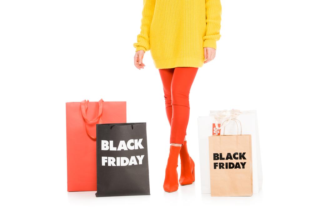 przycięte widzenia stylowa dziewczyna pozuje w pobliżu torby na zakupy na black sprzedaży piątek, na białym tle - Zdjęcie, obraz