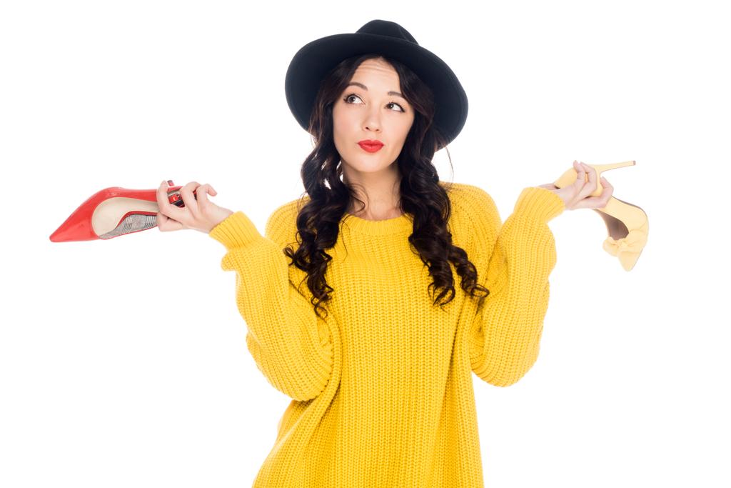 pensativa chica de moda sosteniendo tacones altos aislados en blanco
 - Foto, imagen