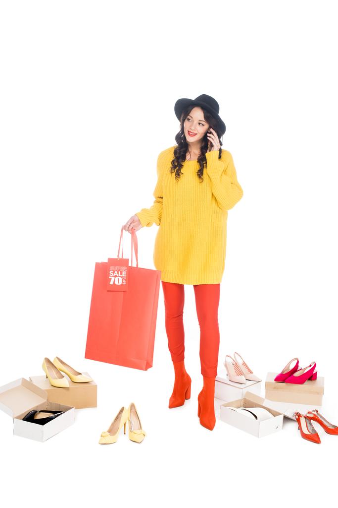 modische Mädchen sprechen auf dem Smartphone und halten Einkaufstasche mit Verkaufsetikett isoliert auf weiß mit Schuhschachteln - Foto, Bild