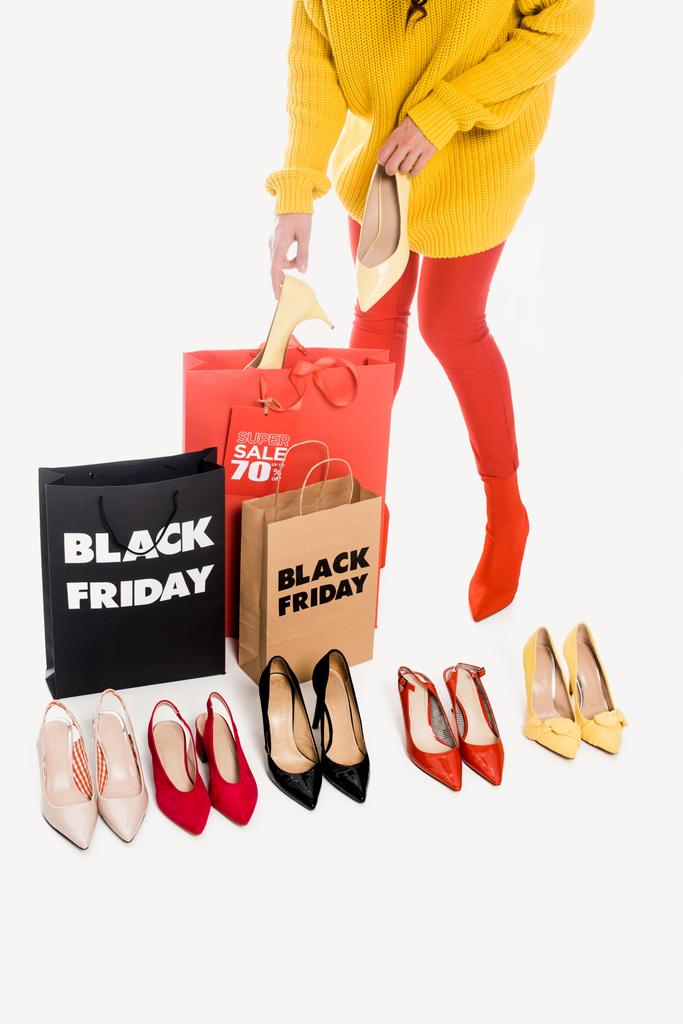 partial view of woman, shopping bags with black friday inscription and stylish female footwear isolated on white - Photo, Image