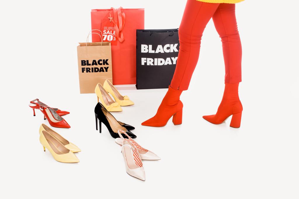 részleges kilátás asszony, bevásárló táskák, elegáns női cipő, elszigetelt fehér és fekete péntek felirat - Fotó, kép