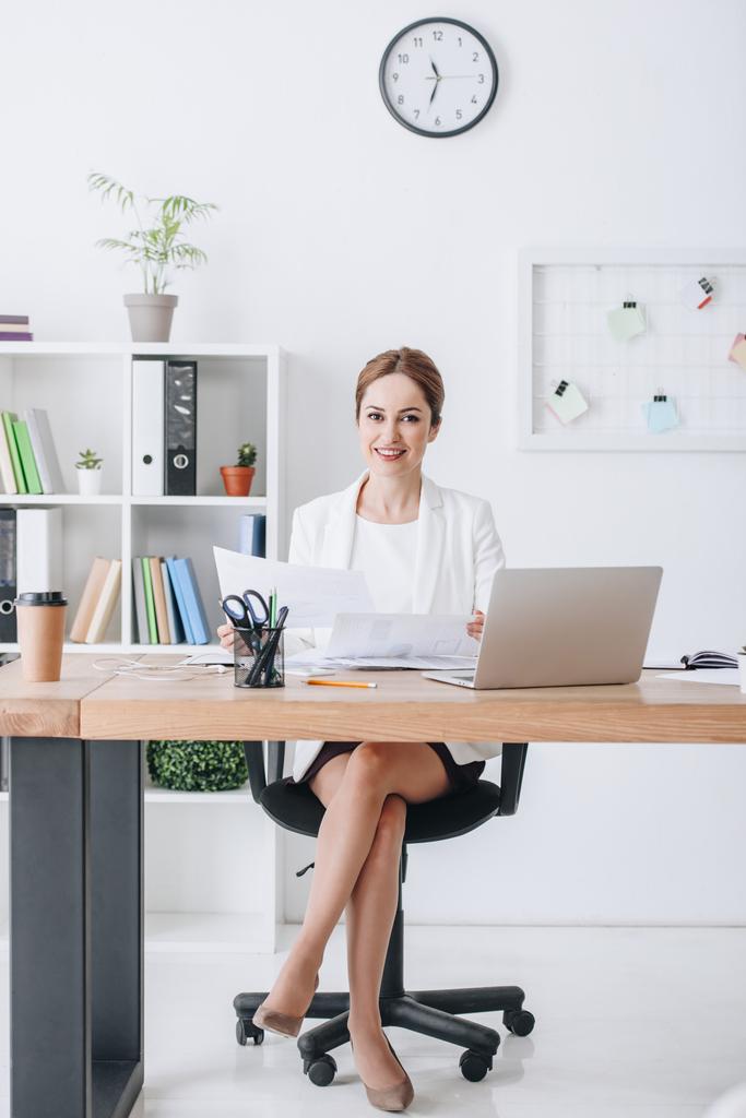 uśmiecha się kobieta biznesu, pracy z dokumentami i laptopa w miejscu pracy w nowoczesnym biurze - Zdjęcie, obraz