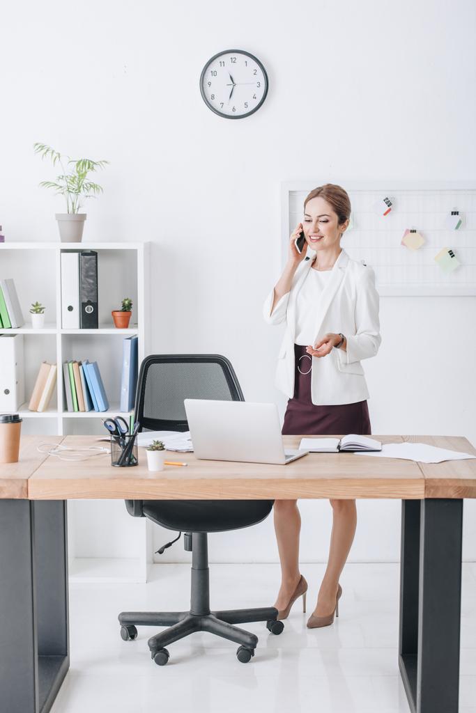 úspěšná podnikatelka, mluví na smartphone v moderní kanceláři s notebookem - Fotografie, Obrázek