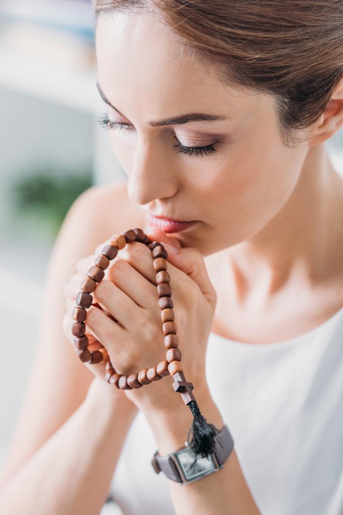 belle femme priant avec des perles de chapelet en bois
 - Photo, image