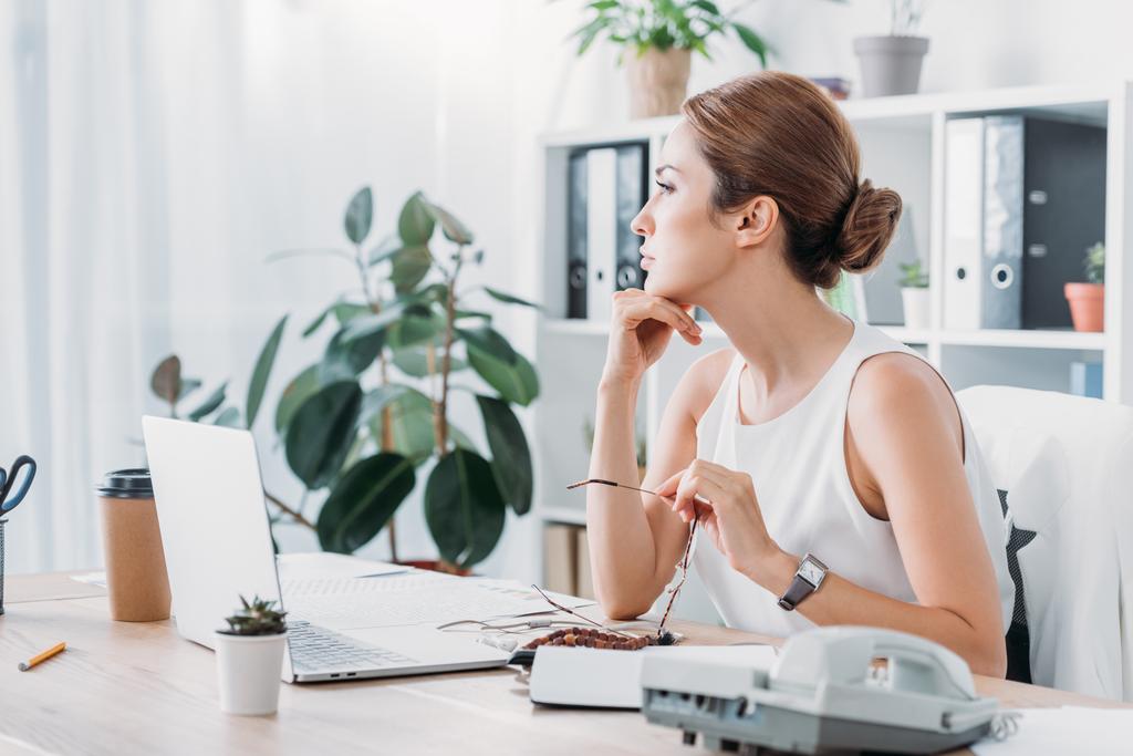 mulher de negócios pensativo sentado no local de trabalho com laptop no escritório moderno
 - Foto, Imagem