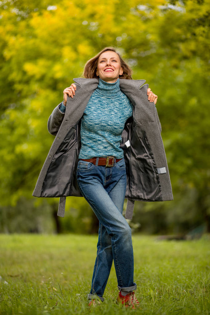 stilvolle Frau in Naturkulisse mit warmem Mantel, die den Frühlingstag oder Herbsttag genießt - Foto, Bild