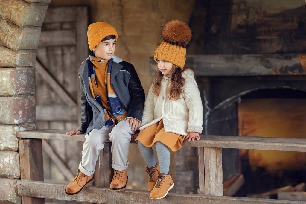 chlapec a dívka sedící na dřevěné zábradlí starého domu společně - Fotografie, Obrázek
