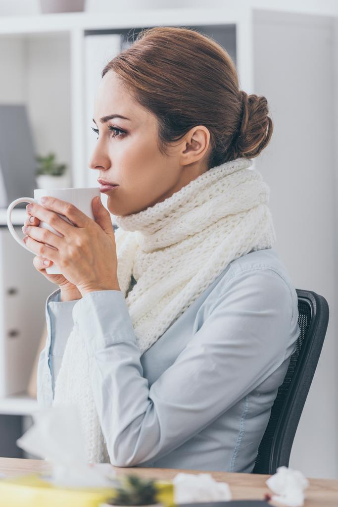 Nahaufnahme Porträt einer kranken Geschäftsfrau im Schal, die im Büro heißen Tee trinkt - Foto, Bild