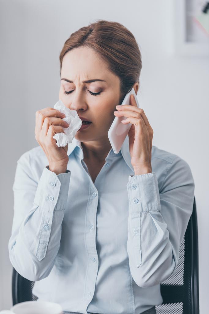 close-up portrait of adult businesswoman with runny nose talking by phone at office - Photo, Image
