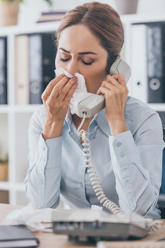 retrato de cerca de la mujer de negocios enferma con secreción nasal hablando por teléfono con cable en la oficina
 - Foto, imagen