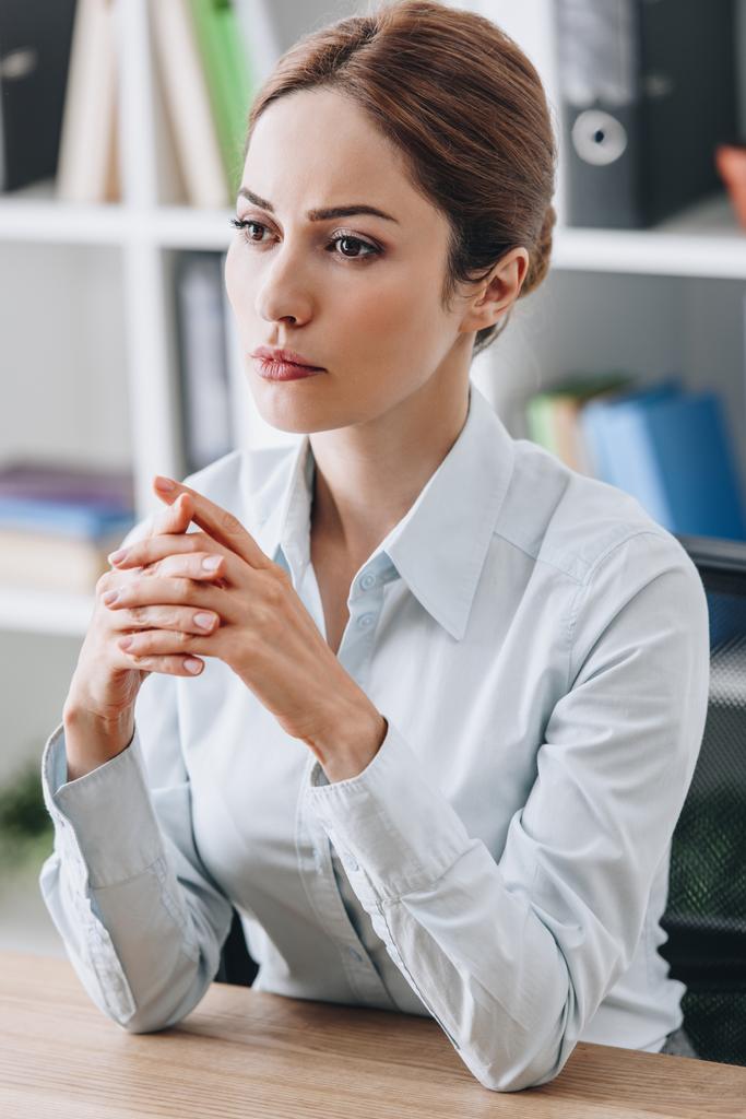 крупным планом портрет вдумчивой деловой женщины, сидящей на рабочем месте и смотрящей в сторону офиса
 - Фото, изображение