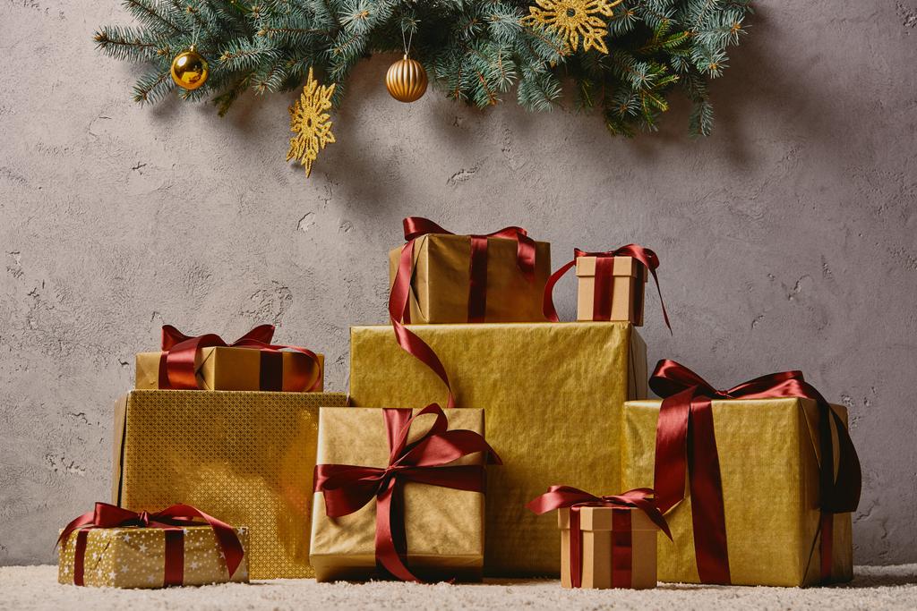 σωρός από χρυσή κουτιά δώρων Χριστουγέννων στο χαλί στην αίθουσα κάτω από το χριστουγεννιάτικο δέντρο - Φωτογραφία, εικόνα