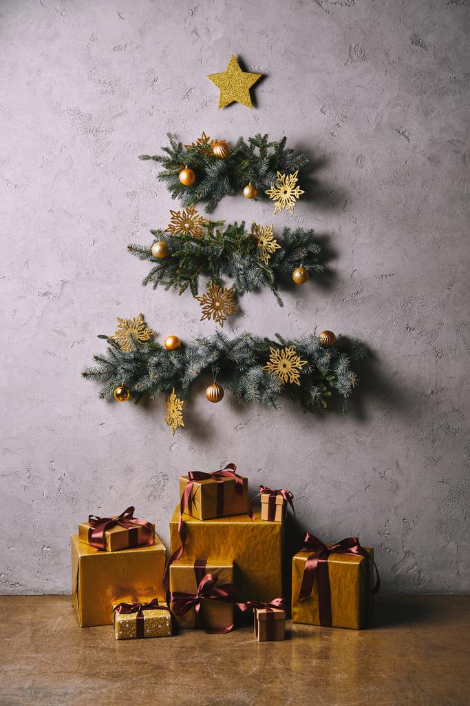 ručně vyráběné vánoční strom vyrobený z větviček visí na šedou stěnu, dárkové krabice na podlaze v pokoji - Fotografie, Obrázek