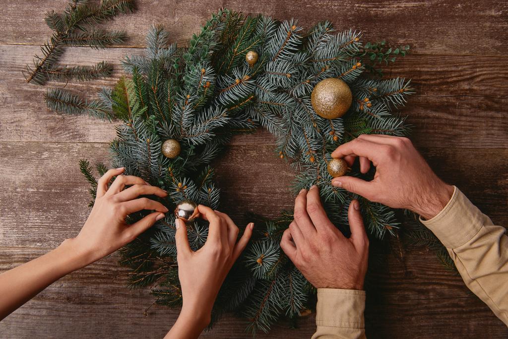 imagen recortada de pareja decorando la corona de abeto de Navidad juntos
 - Foto, Imagen