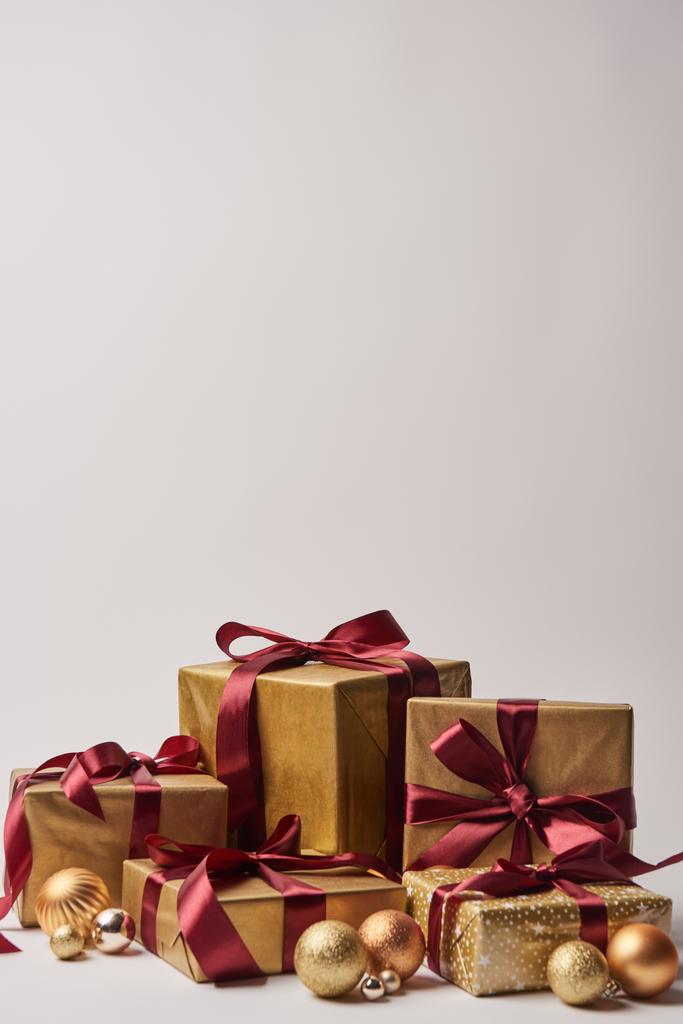 cajas de regalo con cintas de color burdeos y bolas de navidad doradas aisladas en blanco
 - Foto, imagen