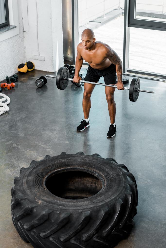 високий кут зору на спортивний голий афроамериканський спортсмен, що піднімає штангу в спортзалі
    - Фото, зображення