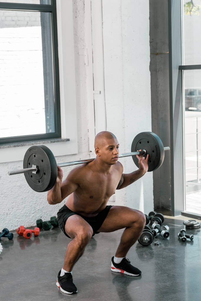 jeune athlète afro-américain homme levant haltère et regardant loin dans la salle de gym
 - Photo, image
