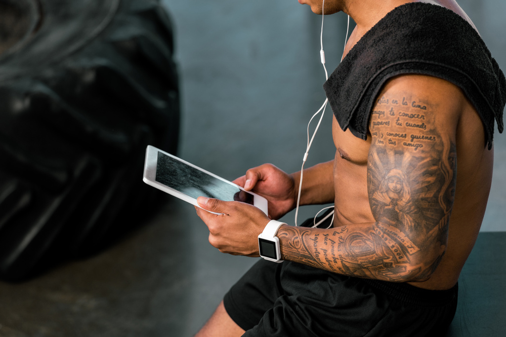 recortado disparo de muscular tatuado deportista utilizando tableta digital en el gimnasio
 - Foto, Imagen