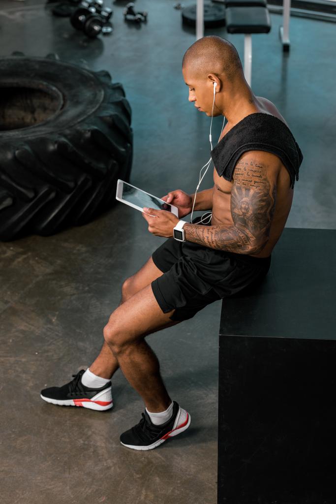 high angle view of young african american sportsman in earphones using digital tablet in gym - Photo, Image