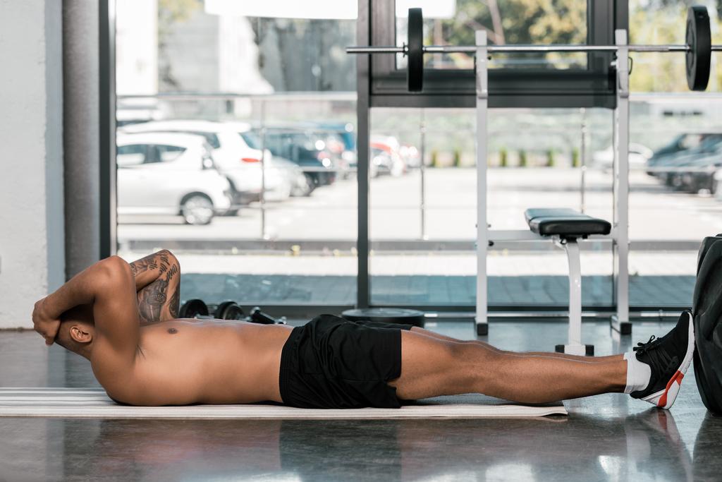 Tetovaný afroamerické muže dělá abs na fitness mat v tělocvičně - Fotografie, Obrázek