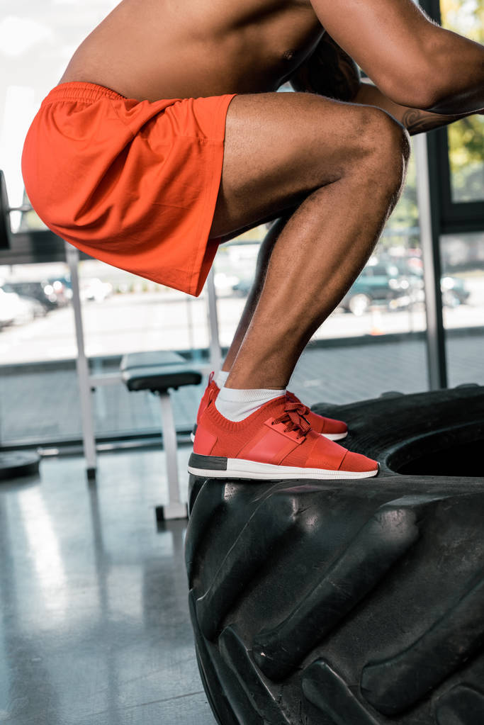imagen recortada de atleta afroamericano haciendo ejercicio sobre neumático en el gimnasio
 - Foto, imagen