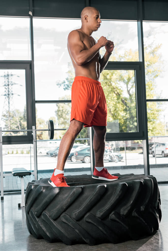 guapo afroamericano atleta haciendo ejercicio en neumático en gimnasio
 - Foto, imagen