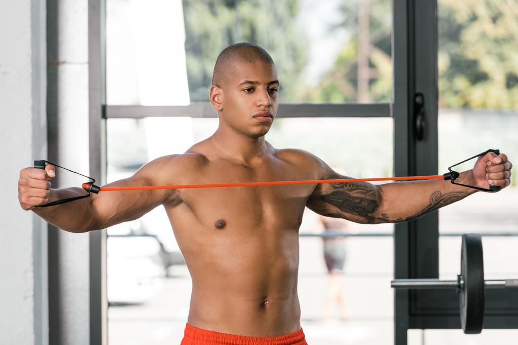 atleta muscular sin camisa haciendo ejercicio con banda de estiramiento en el gimnasio
 - Foto, imagen