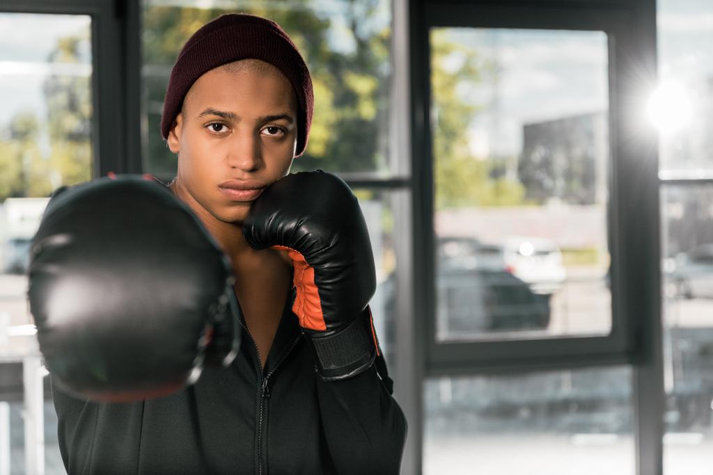 молодой афроамериканец боксер в боксёрских перчатках, тренирующийся в спортзале
 - Фото, изображение