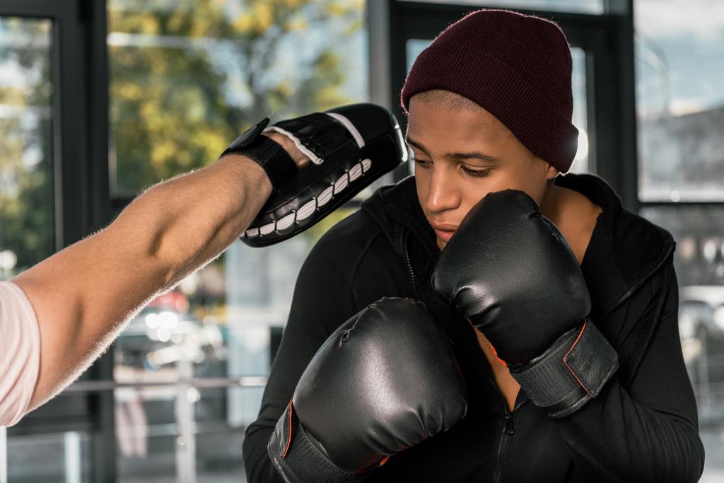 Selektywny fokus z Afryki amerykański bokser w Rękawice bokserskie, ćwiczenia z trenerem na siłowni - Zdjęcie, obraz